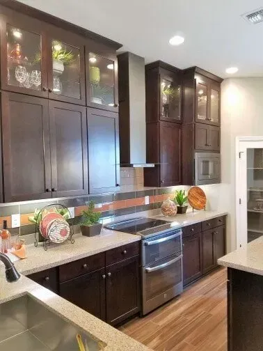 A kitchen with wooden cabinets , stainless steel appliances , a sink , and a stove.
