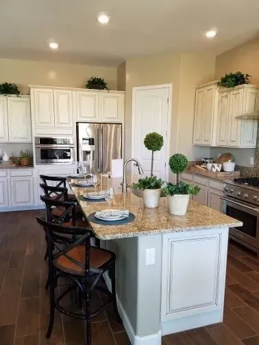 A kitchen with a large island , stainless steel appliances , granite counter tops and white cabinets.