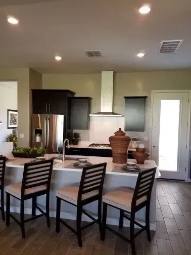 A kitchen with a large island and three chairs.