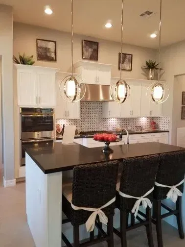 A kitchen with white cabinets and black counter tops.