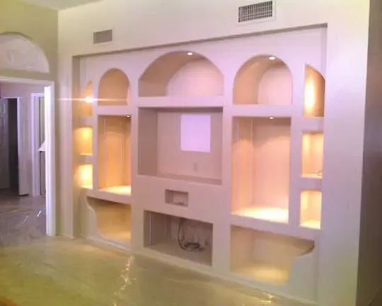 A wall with a lot of shelves and a tv on it.