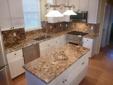 A kitchen with granite counter tops , stainless steel appliances , and white cabinets.