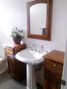 A bathroom with a sink , mirror and wooden cabinets.