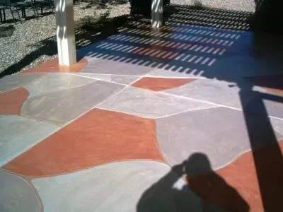 A shadow of a person is cast on a colorful concrete floor.