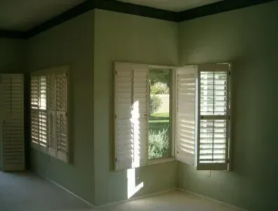 A corner of a room with white shutters