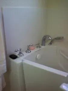 A white bathtub with chrome faucets and soap on the side of it in a bathroom.