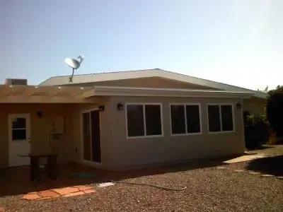 A house with a lot of windows and a satellite dish on the roof.