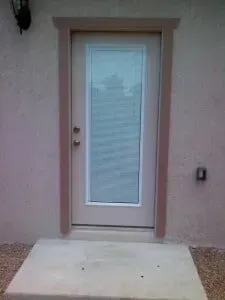 A white door with a glass window is sitting on top of a concrete step.