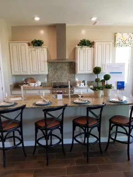 A kitchen with a stove , sink , chairs and plates on the counter.