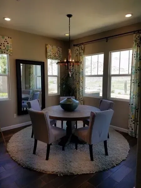 A dining room with a round table and chairs and a mirror.