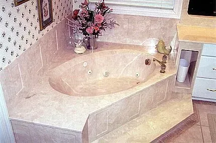 A bathroom with a jacuzzi tub and a vase of flowers on the counter.