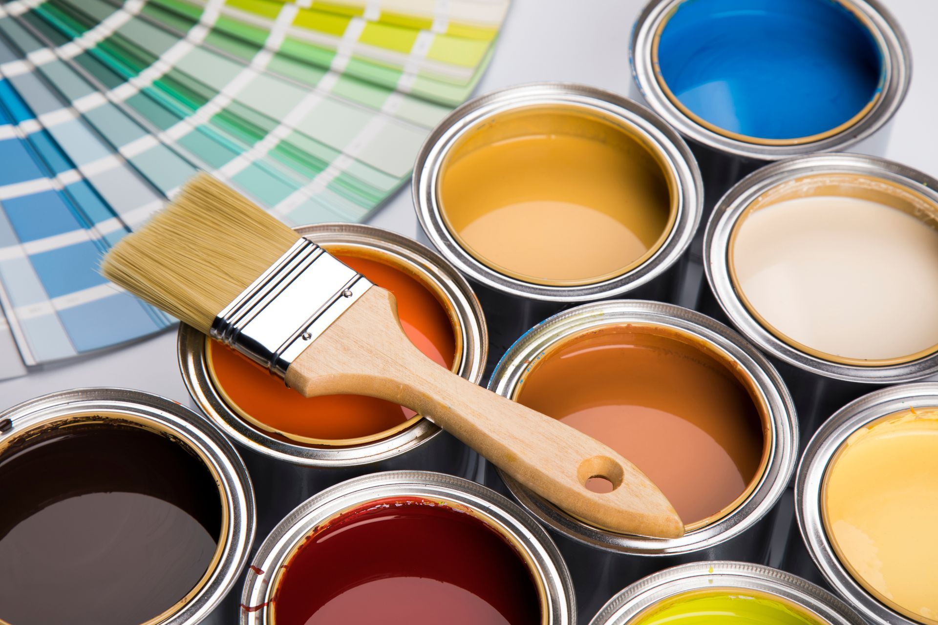 Open paint cans and color swatches with brush for home painting color selection in Surprise, AZ