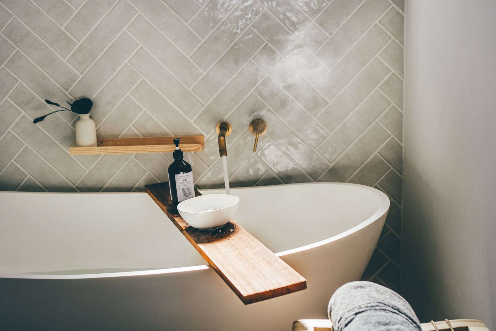 A person is sitting in a bathtub with a wooden tray on it.
