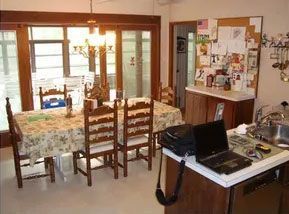 A kitchen with a table and chairs and a laptop on the counter.