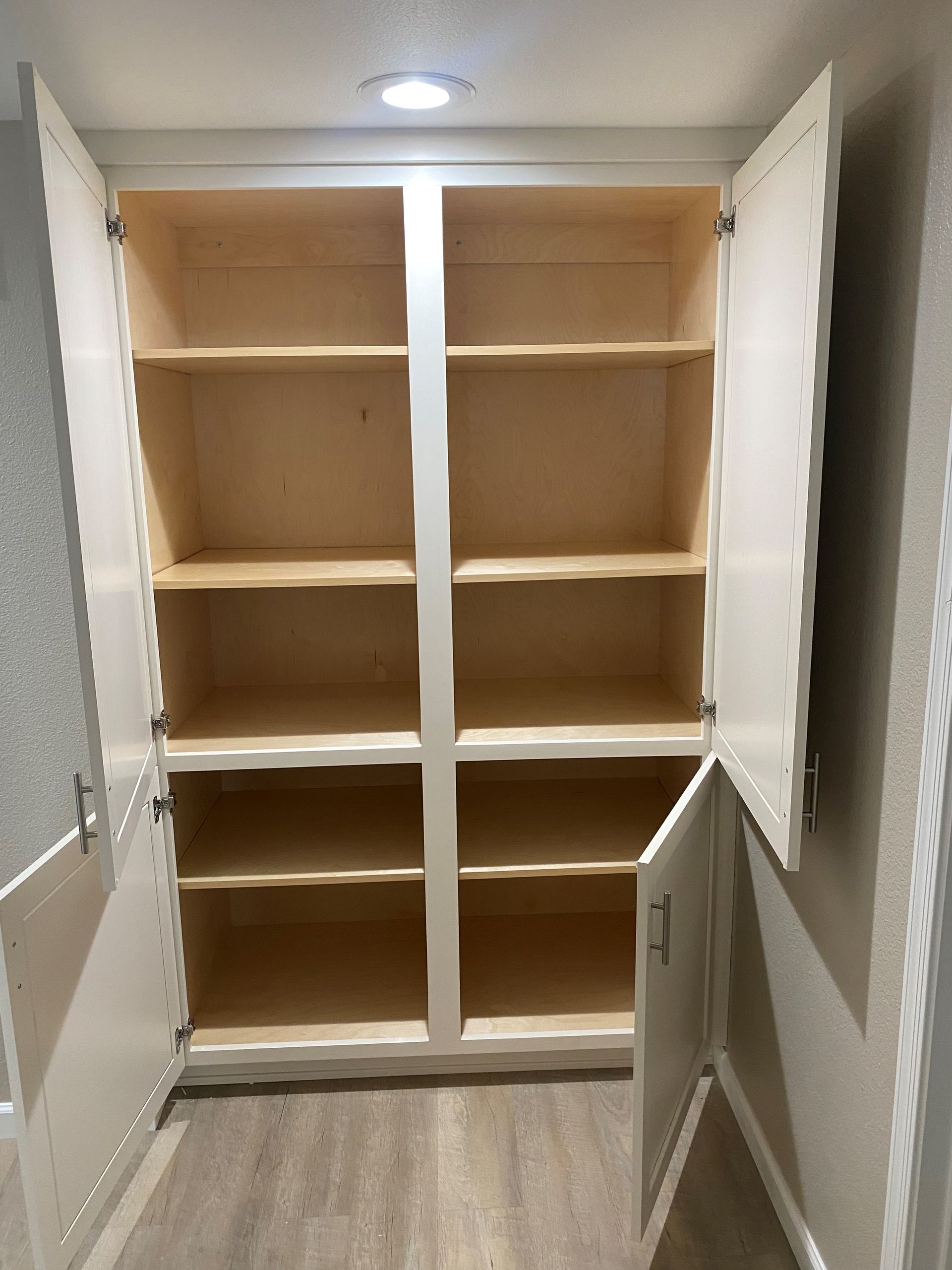An empty cabinet with the doors open in a hallway.
