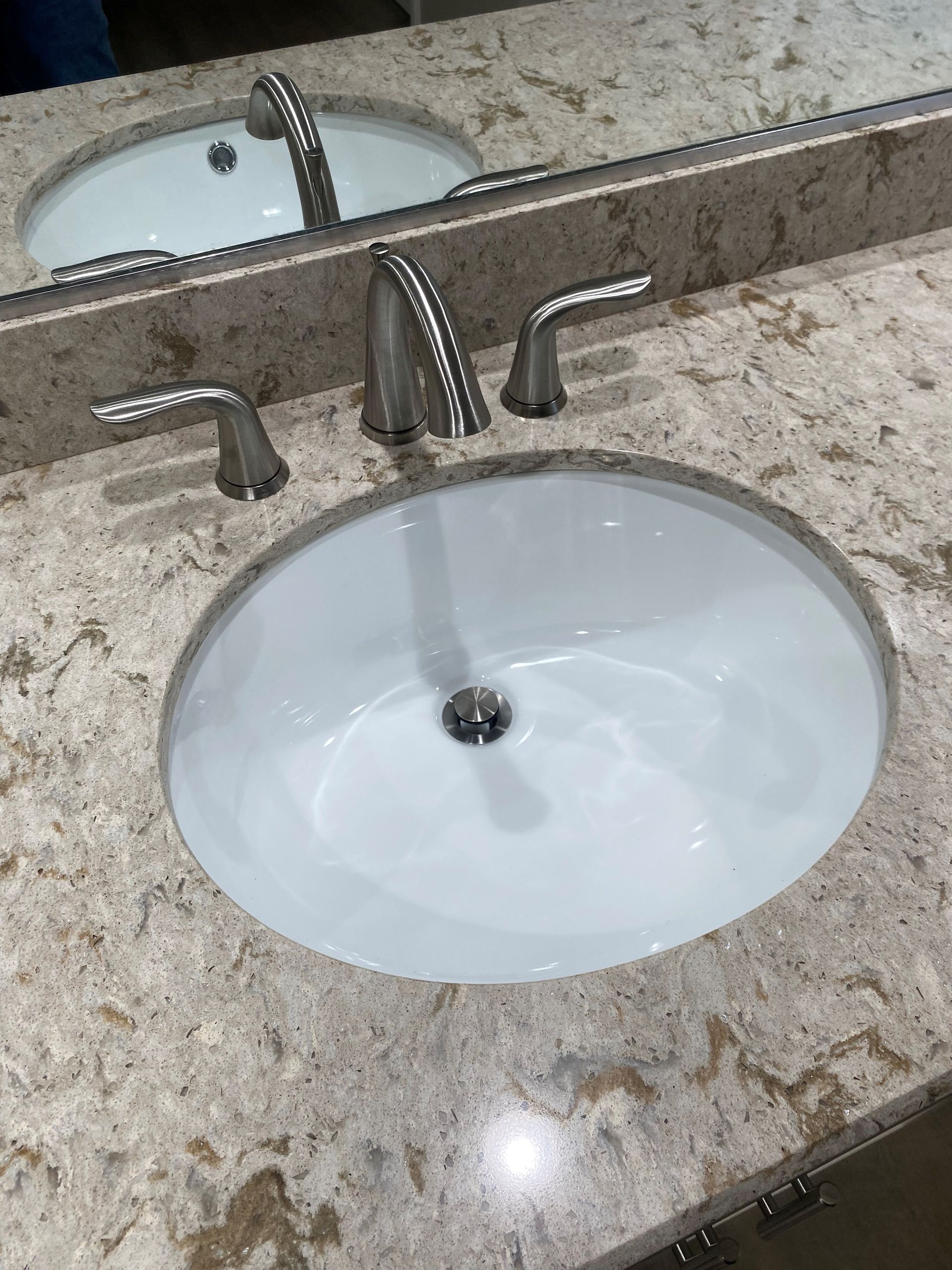A bathroom sink with two faucets and a mirror.