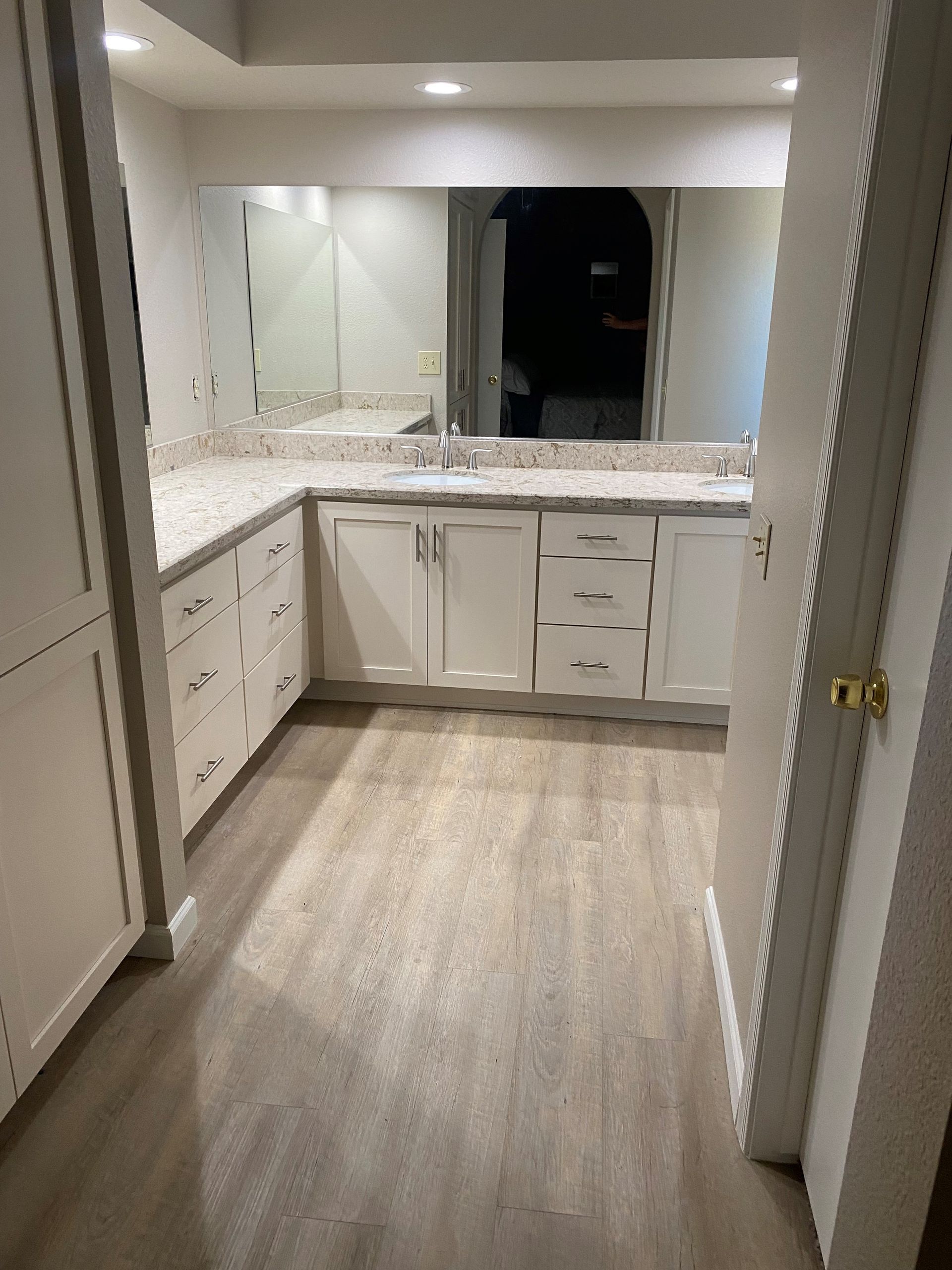A bathroom with white cabinets and a large mirror.