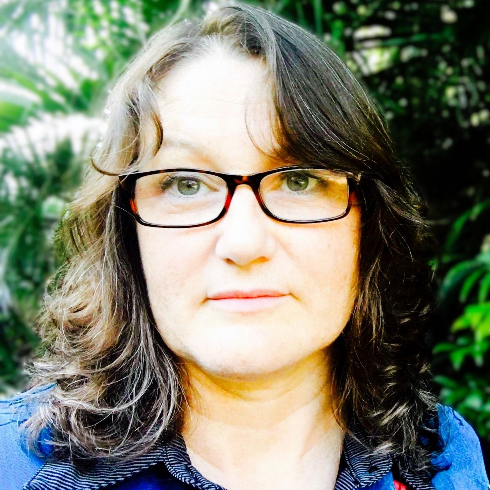 A woman wearing glasses and a blue shirt looks at the camera. Michelle Maloney.