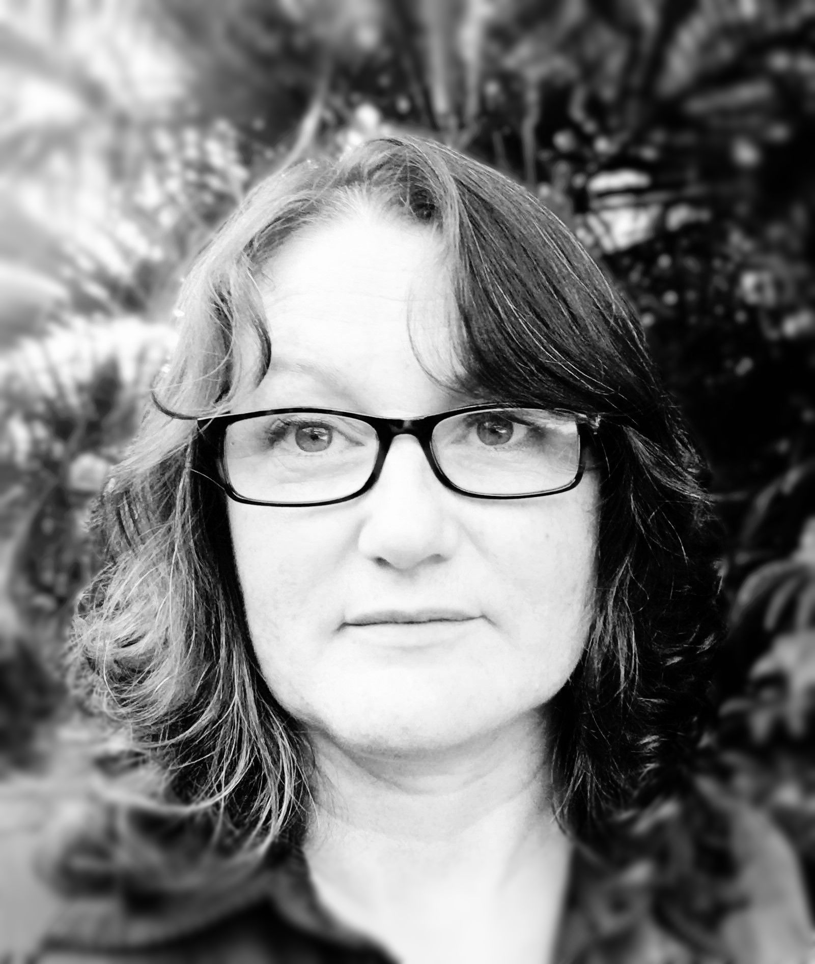 A black and white photo of a woman wearing glasses. Michelle Maloney.