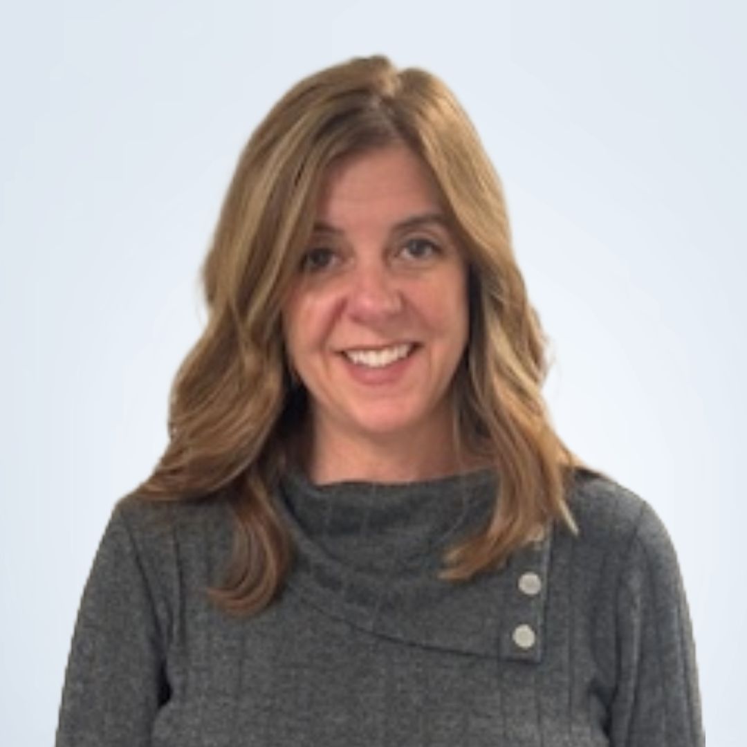 Woman with shoulder-length blonde hair smiling; wearing a gray sweater with buttons.