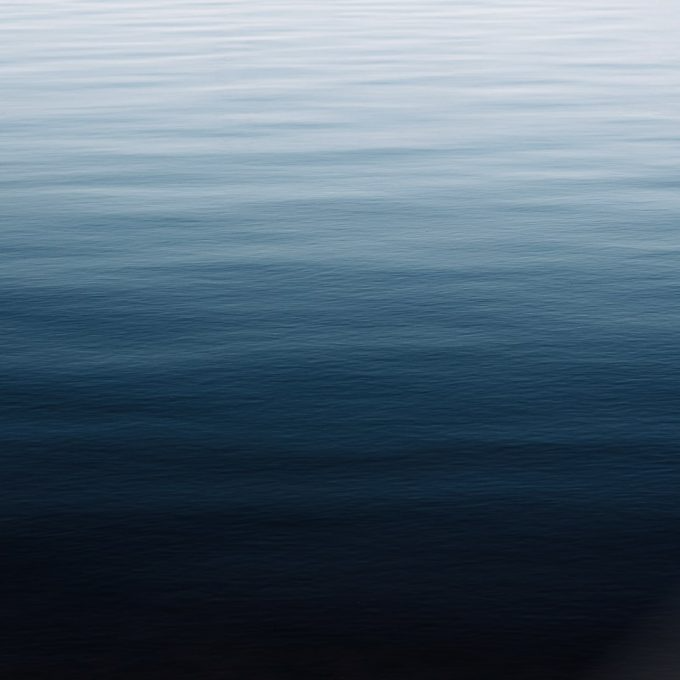 Calm ocean water, ranging from light blue to dark blue, with gentle horizontal waves.