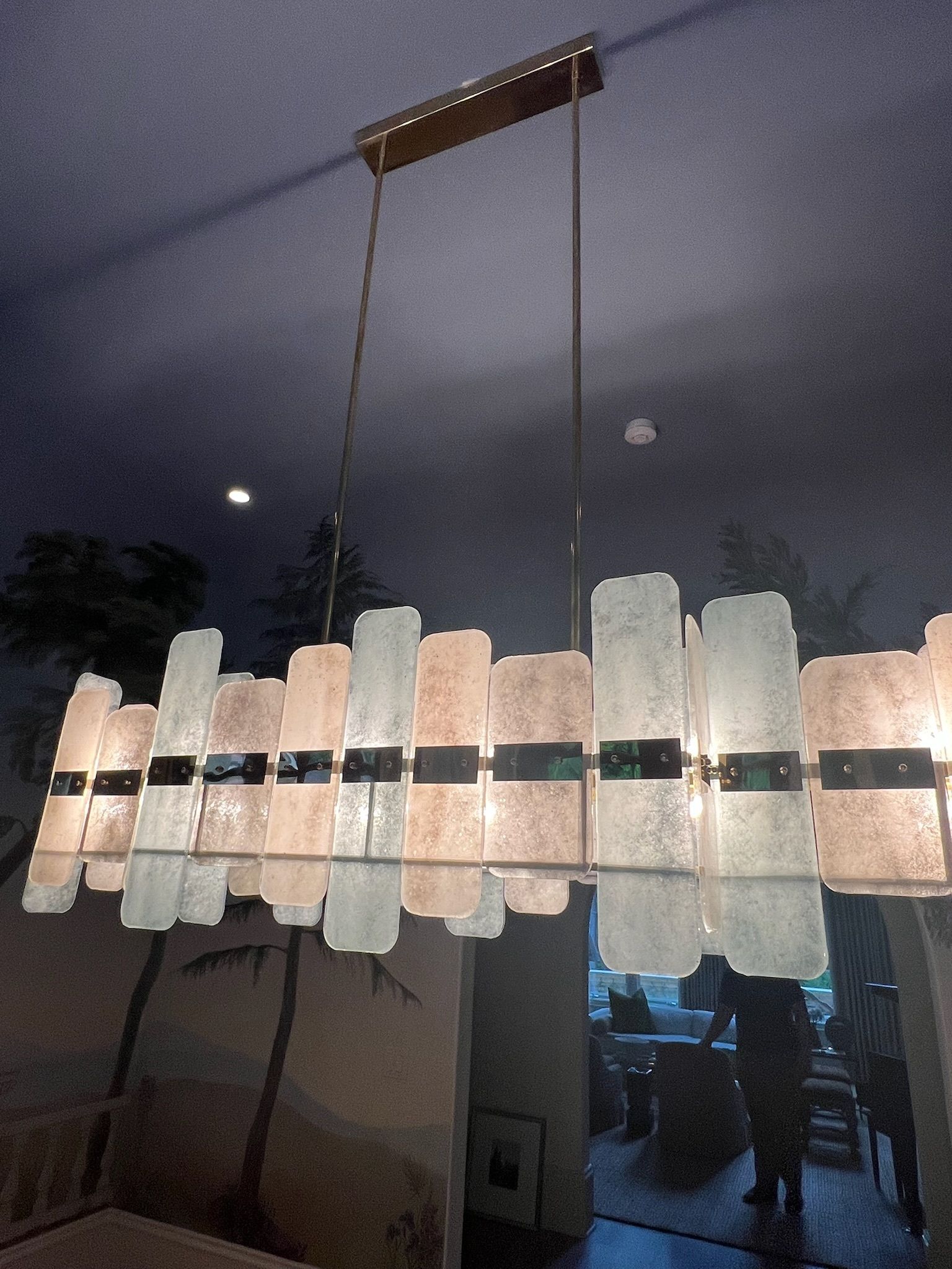 Rectangular chandelier with frosted glass panels, hanging from a gold frame. Interior setting.