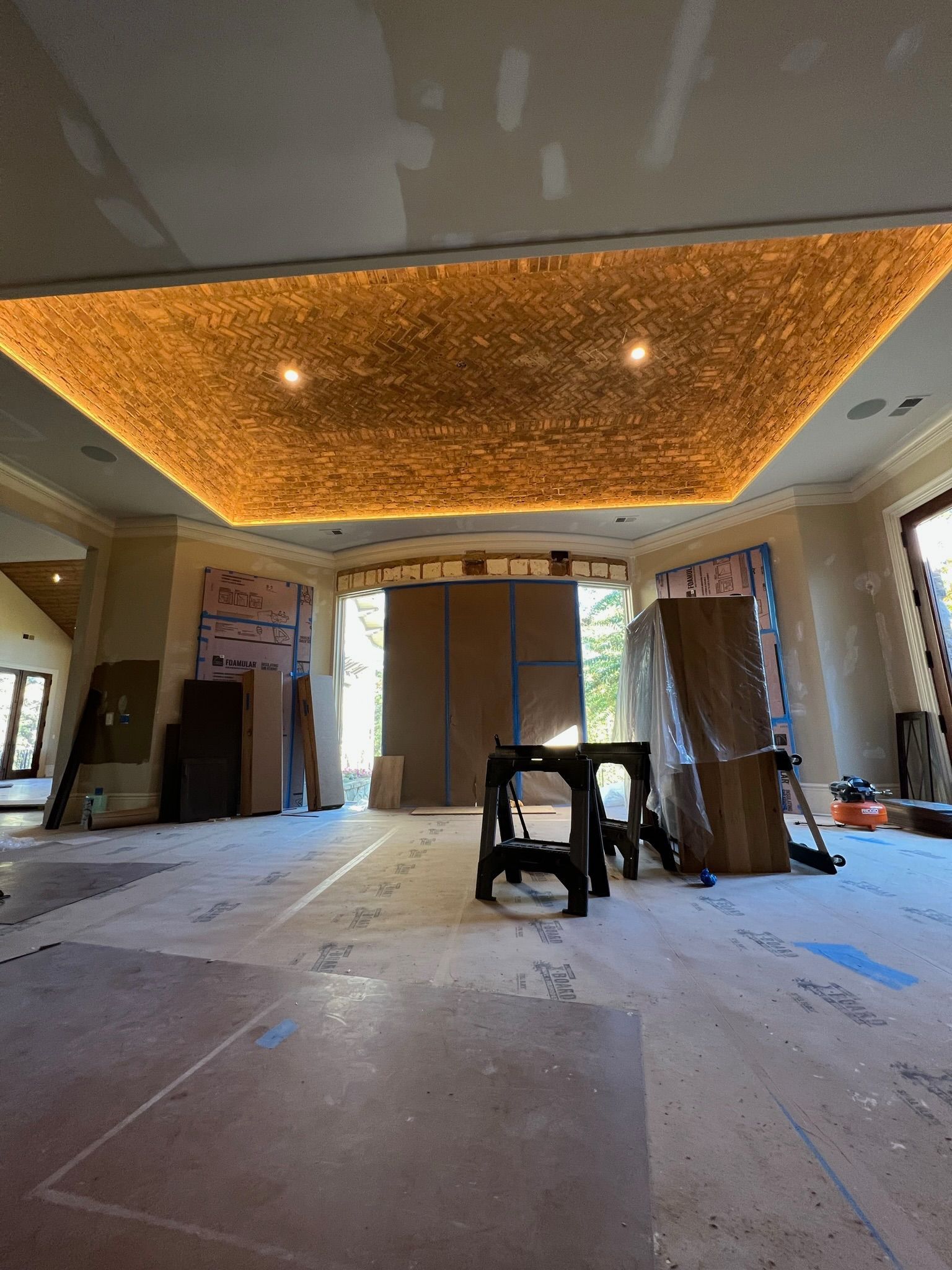 Room under construction with textured ceiling, warm lighting, and plywood walls.