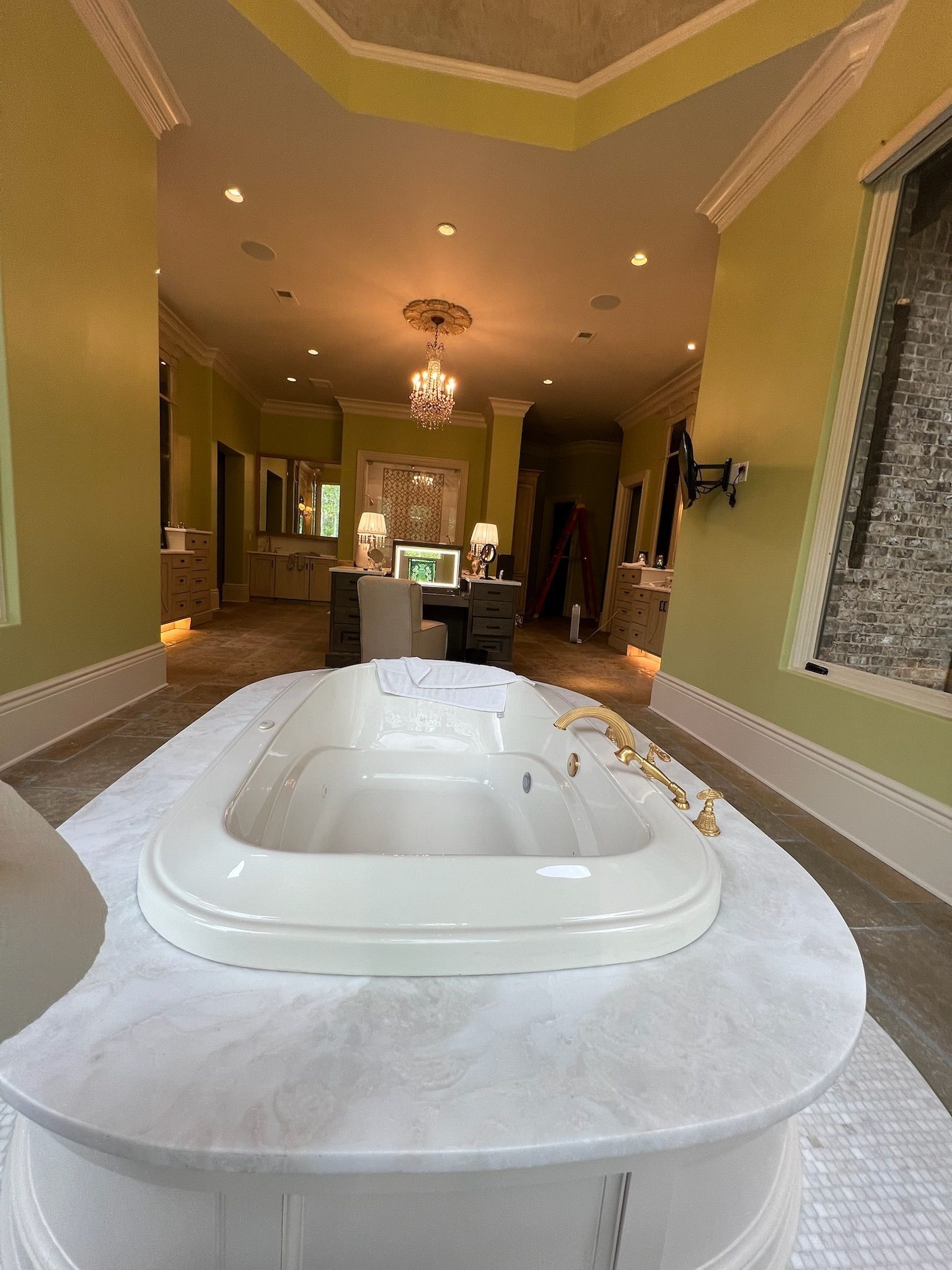 Luxurious bathroom with a large tub, green walls, and marble accents.