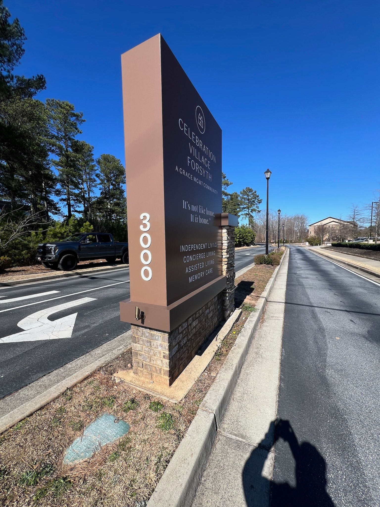 Signpost with business listings and address 3000, next to a road, blue sky.