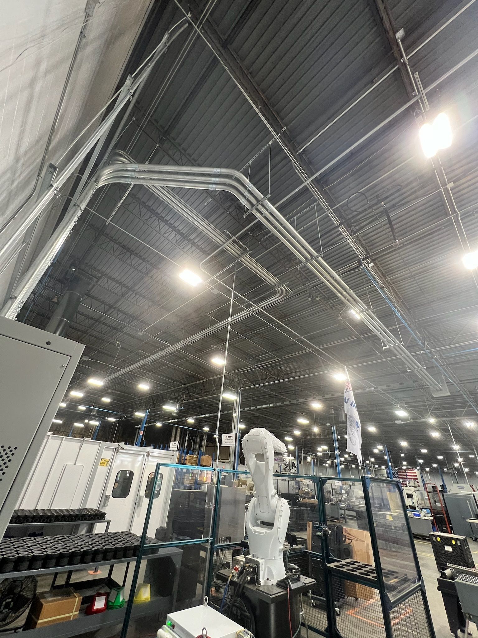 Industrial factory interior with overhead conduit and robotic arm.