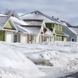 A row of houses covered in snow on a sunny day.