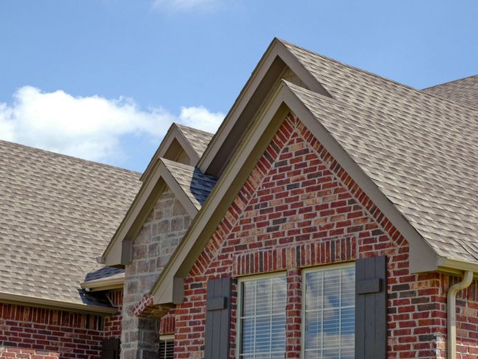 A brick house with a brown roof and black shutters