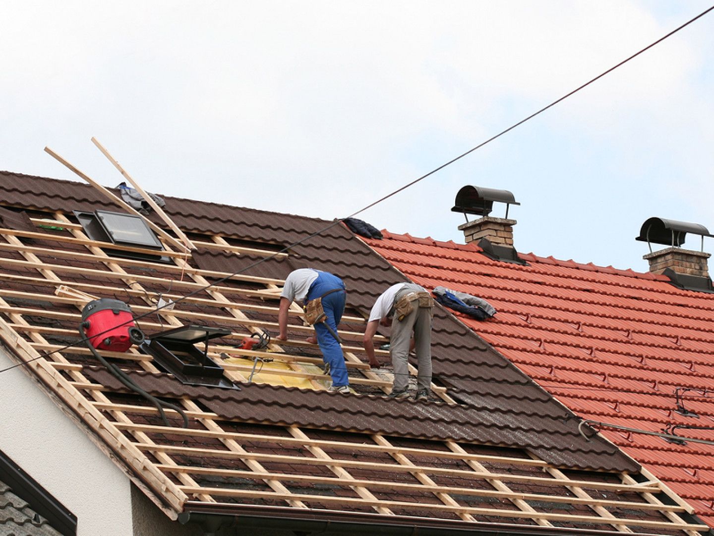 Two men are working on the roof of a house