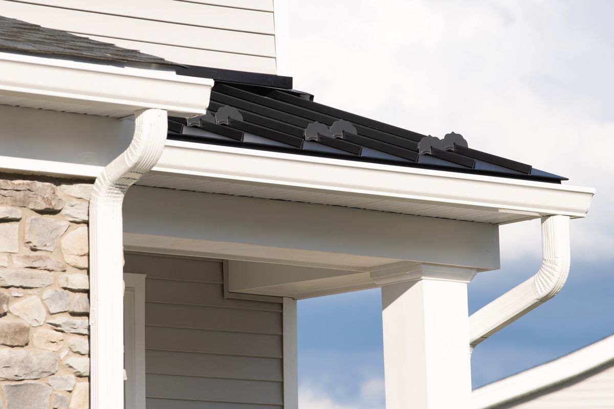 A white house with a black roof and a white gutter.