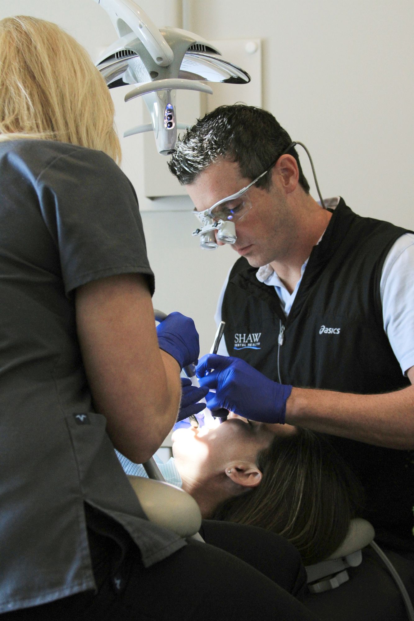 a dentist wearing a black vest with the word shaw on it