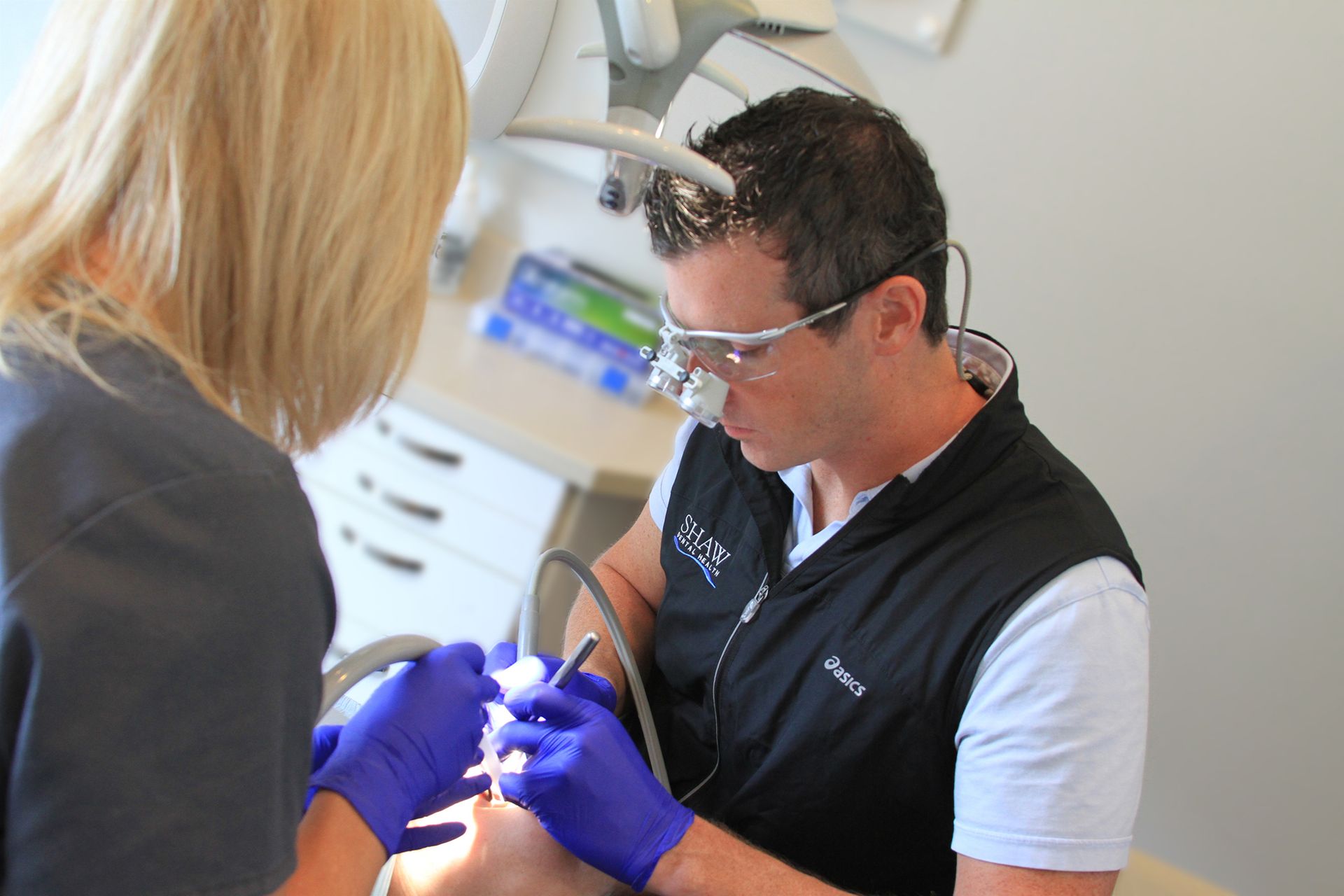 A dentist is examining a patient 's teeth in a dental office
