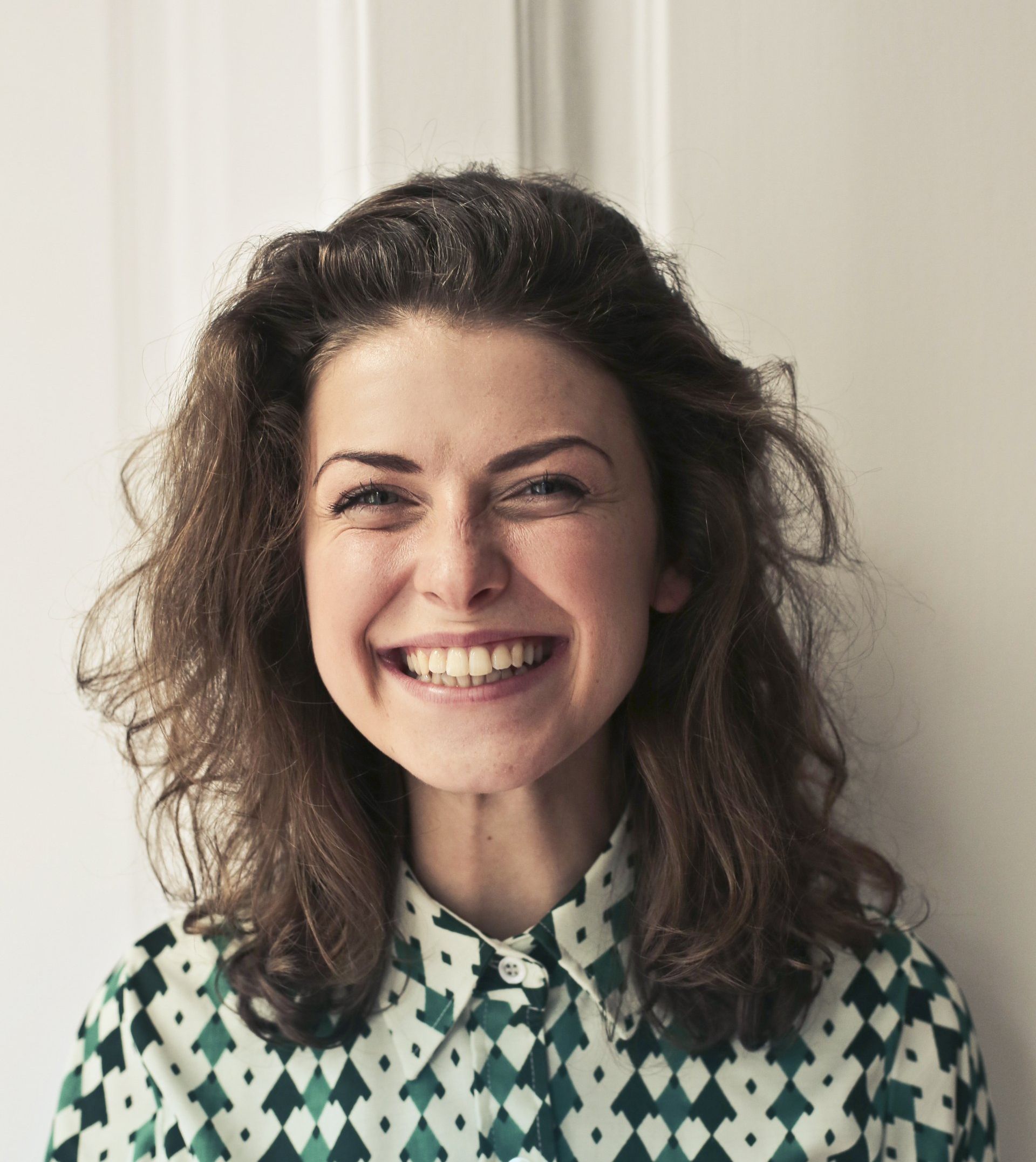 a woman wearing a green and white shirt is smiling