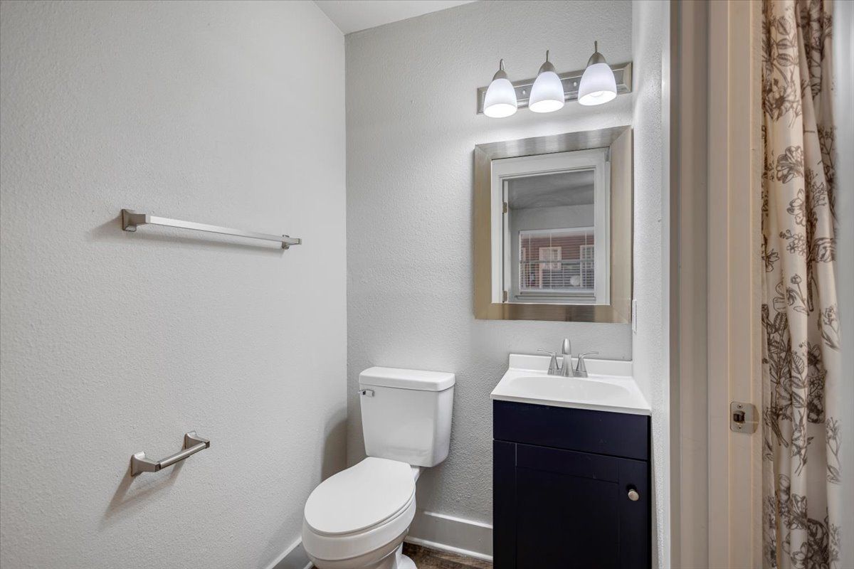 Small bathroom with toilet, sink, mirror, and light fixture; gray walls.
