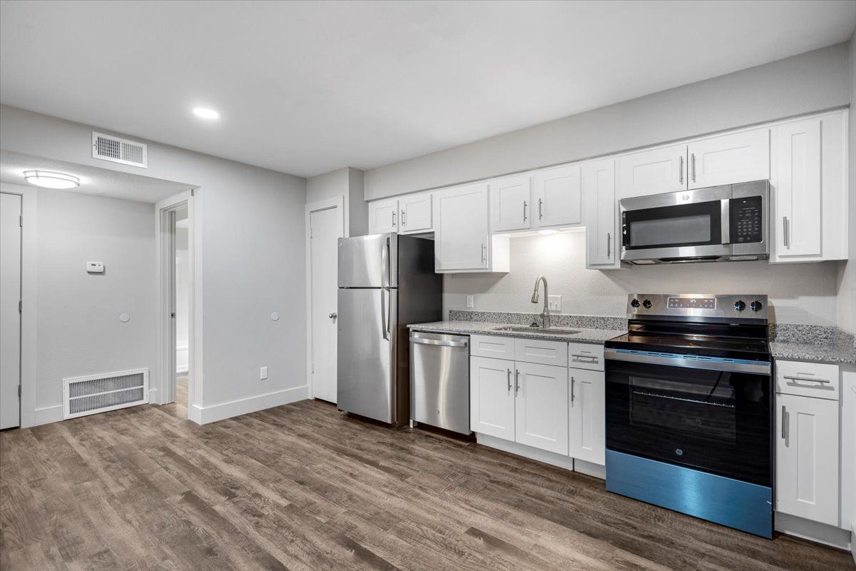 Kitchen with white cabinets, stainless steel appliances, and wood-look flooring.