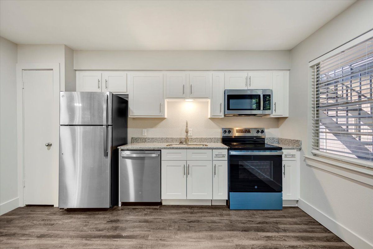 Modern kitchen with stainless steel appliances, white cabinets, and granite countertops.