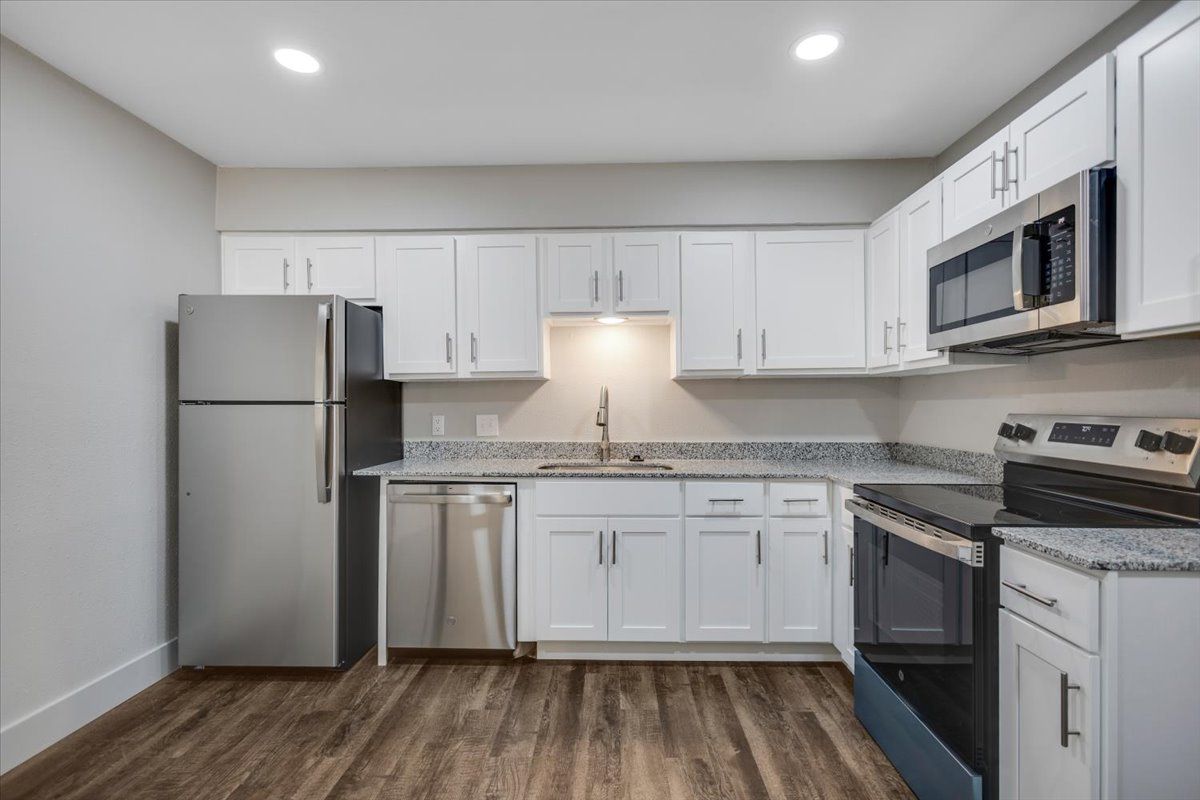 Modern kitchen with white cabinets, stainless steel appliances, and gray countertops.
