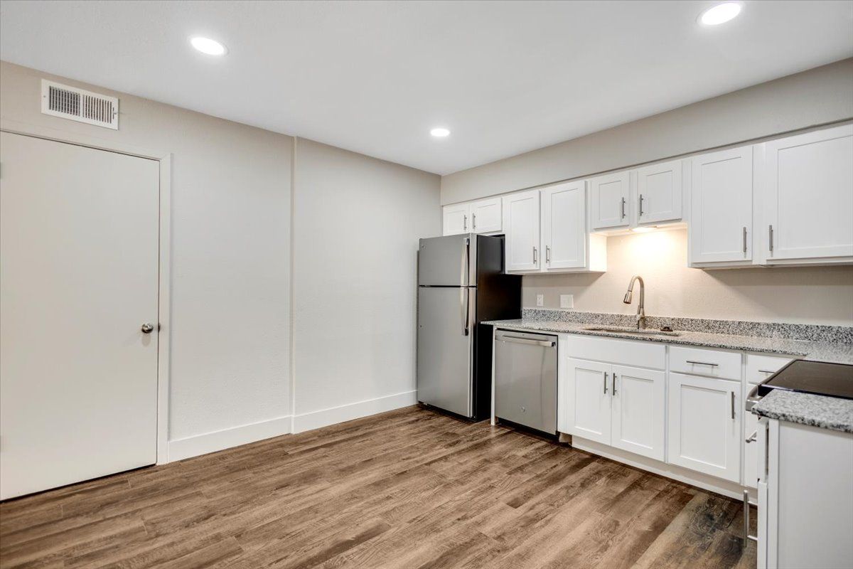 Kitchen with white cabinets, stainless steel appliances, and wood-look flooring.