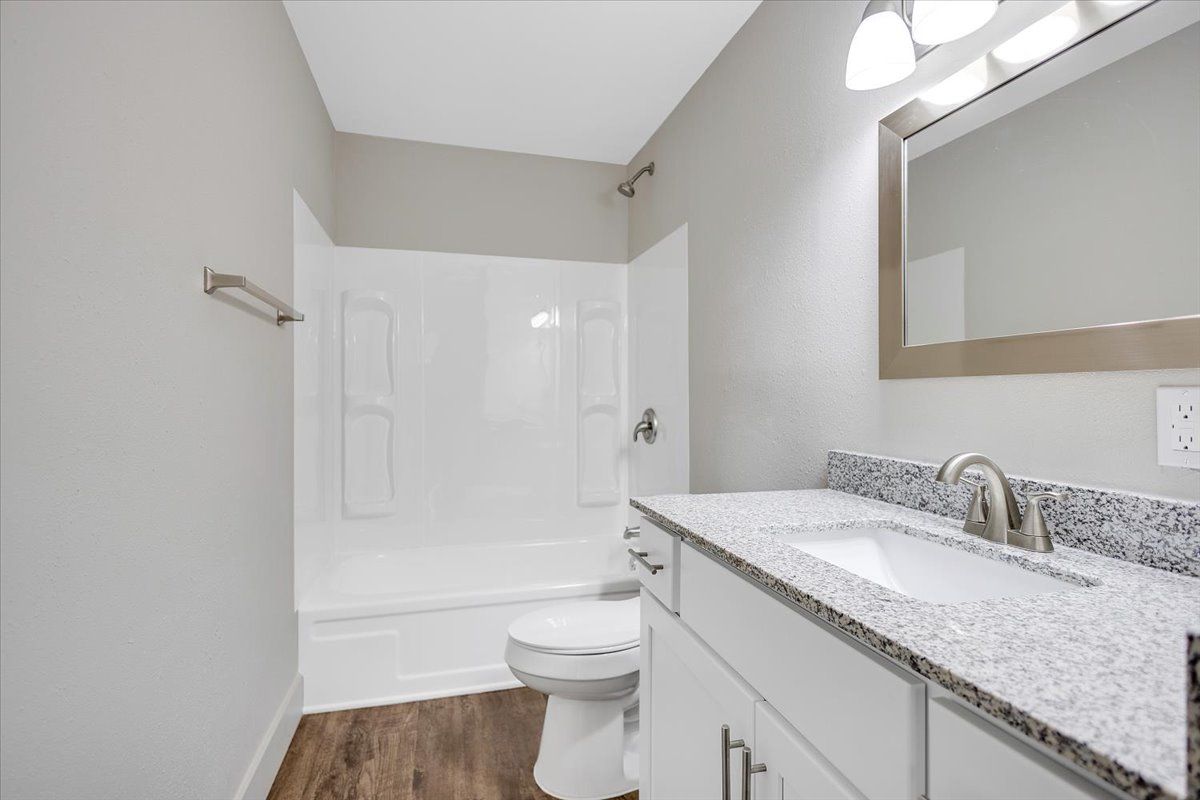 Bathroom with white vanity, gray countertop, white tub/shower, and light gray walls.