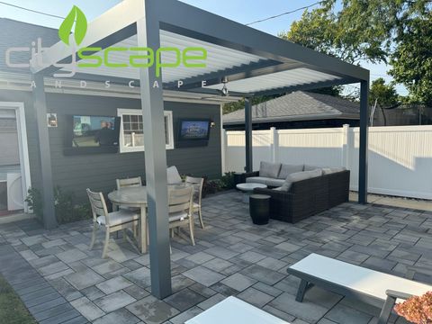 Rooftop deck with seating, wooden pergola, and cityscape background. Black metal railing in foreground.