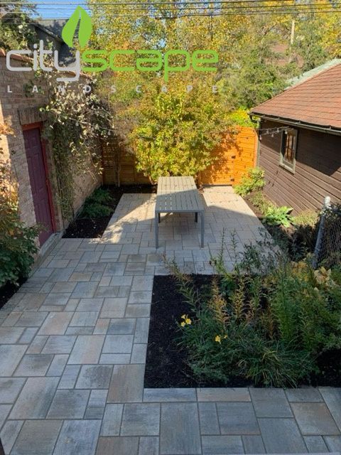 Outdoor bar with stools, TV, and overhead lighting under a deck at night. Cityscape Landscape logo on the left.