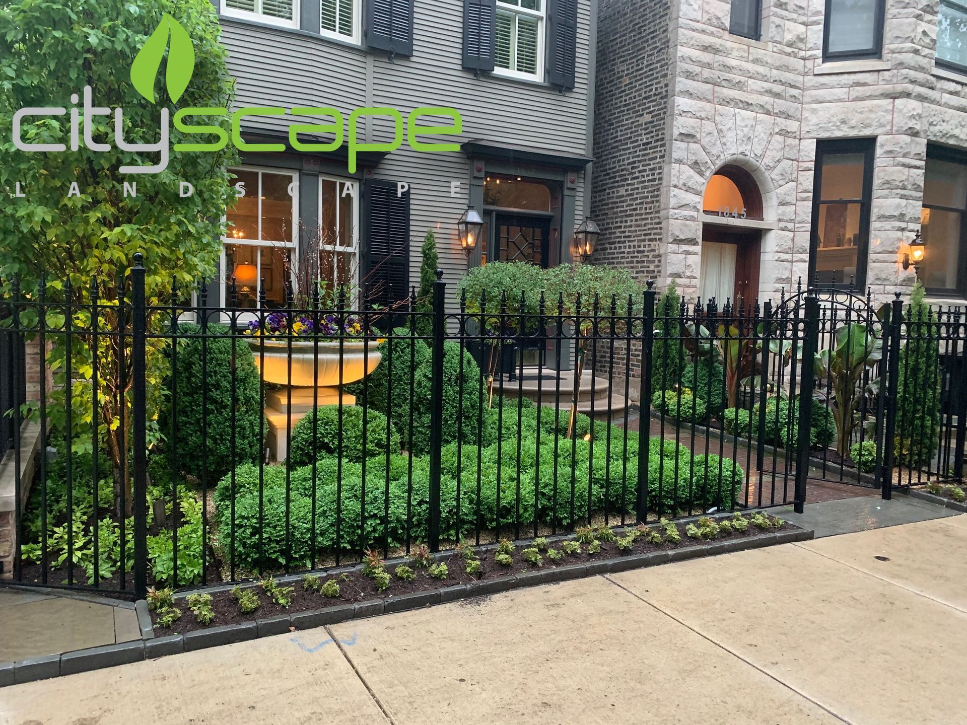 Backyard patio with bar, hot tub, and fire pit. Brick house, green grass, and gray pavers. Cityscape logo visible.
