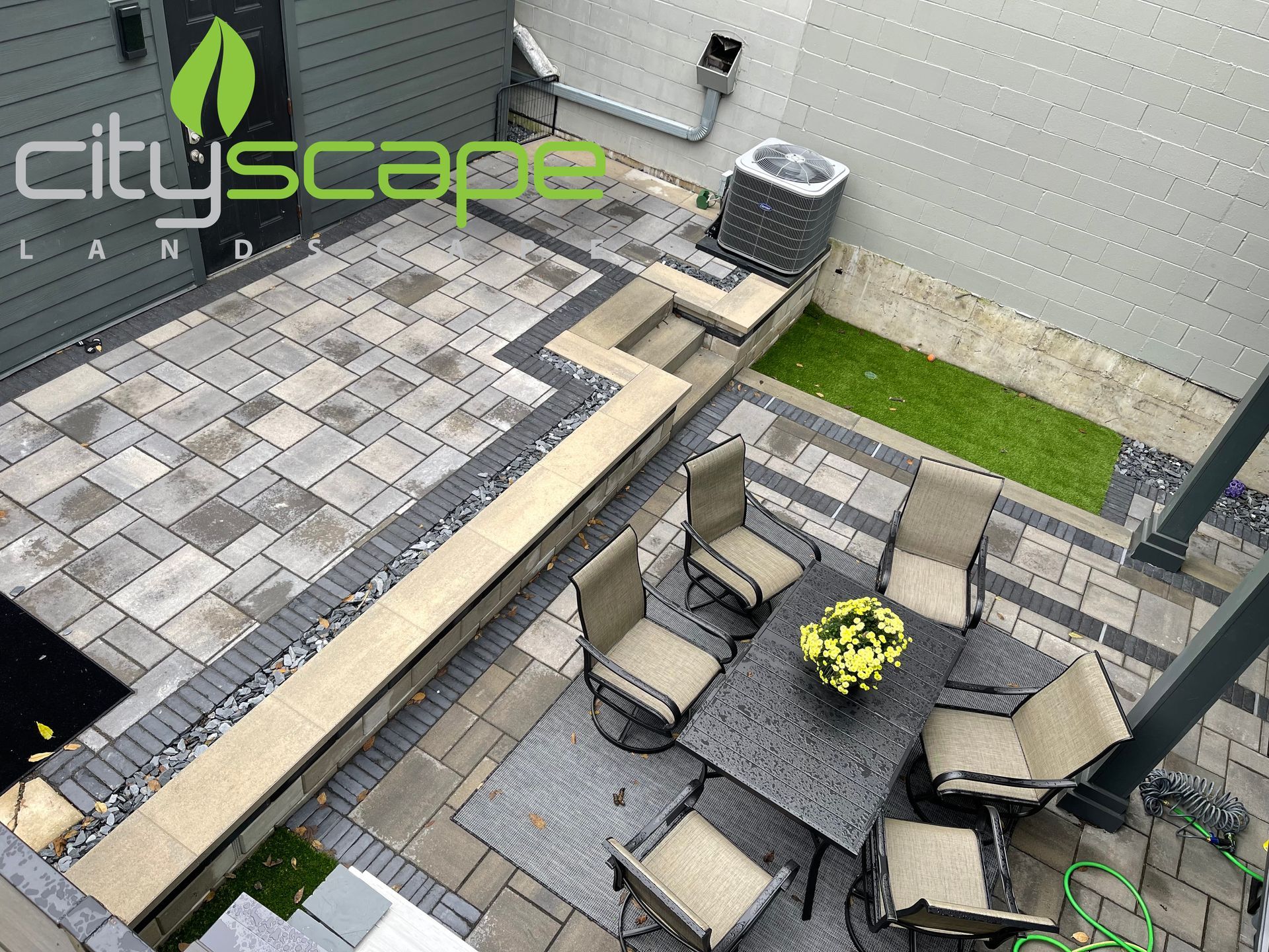 Overhead view of a modern backyard patio with pavers, seating, and a small green space.