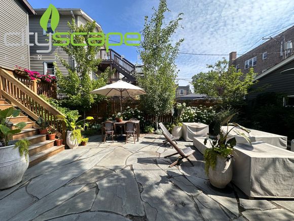 Patio with covered outdoor furniture, a black metal staircase, and brick wall.