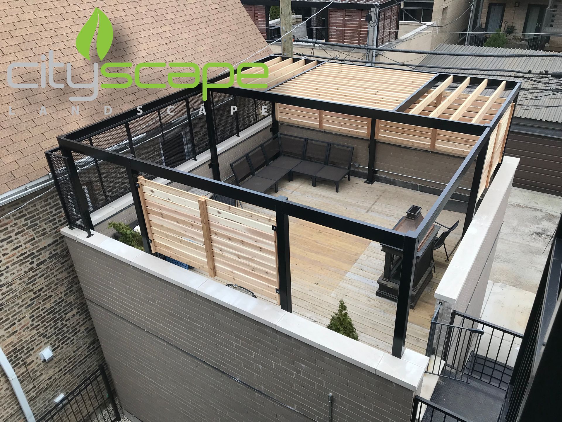 Rooftop patio with black pergola, wood slats, and gray seating.