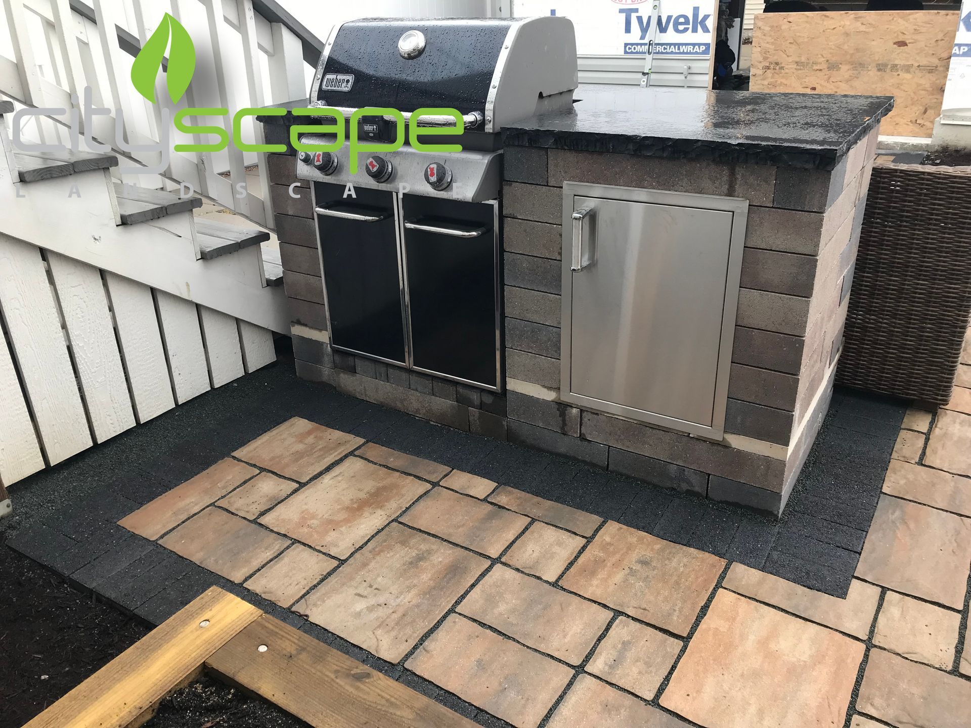 Outdoor grill station with a brick facade on a paved patio.